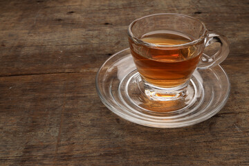 Hot tea in transparent glass cup saucer on rustic wood background