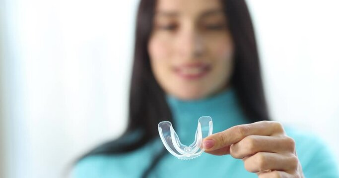 Woman holding plastic night guard teeth closeup 4k movie slow motion. Bruxism treatment concept