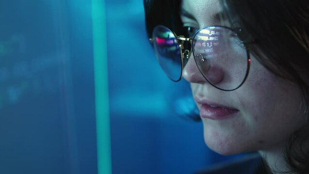 Close-up image of female face, programmer, software developer looking on digital screen with coding information. Reflection of code on glasses. Profession, occupation , IT, modern technologies concept