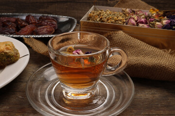Baklava sweet dessert  date fruit liquid honey natural geomatic hexagon bee wax honeycomb flower tea rose bud butterfly pea chamomile flower tea in transparent glass cup saucer on rustic wood table ba