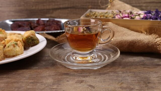 Baklava sweet dessert  date fruit liquid honey natural geomatic hexagon bee wax honeycomb flower tea rose bud butterfly pea chamomile flower tea in transparent glass cup saucer on rustic wood table ba