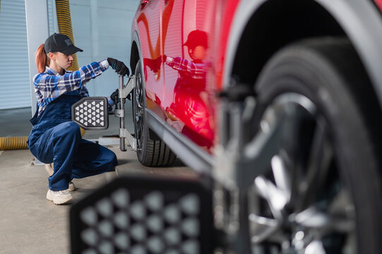 A female auto mechanic makes a camber. Woman working in a car service.