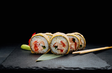 Warm sushi roll with tuna on a black stone
