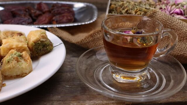 Baklava sweet dessert  date fruit liquid honey natural geomatic hexagon bee wax honeycomb flower tea rose bud butterfly pea chamomile flower tea in transparent glass cup saucer on rustic wood table ba
