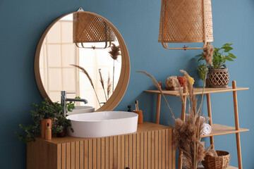 White sink with bath accessories on chest of drawers and houseplants near color wall