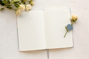 Blank open notebook and beautiful rose flowers on light background