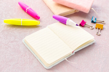 Blank open notebook, markers and binder clips on light background