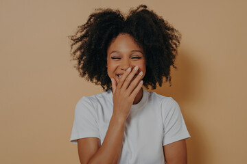 Beautiful dark skinned millennial woman covering her mouth with hand while laughing - Powered by Adobe