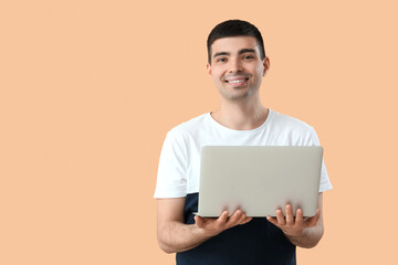 Young man with laptop on beige background