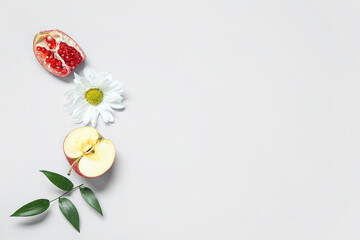 Composition with ripe apple, pomegranate, flower and plant leaf on light background. Rosh hashanah (Jewish New Year) celebration