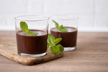 Chocolate mousse dessert garnished with mint leaf on wooden table and white background. Copy space