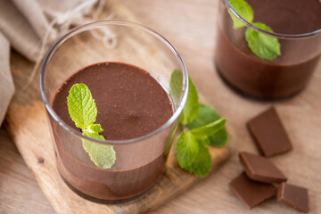 Chocolate mousse dessert garnished with mint leaf on wooden table and white background