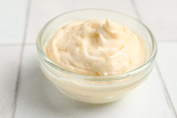 Bowl with tasty cream cheese on white tile background