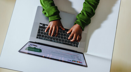 Young hands on a keyboard: Child coding with a laptop in a classroom