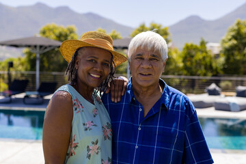 Portrait of happy senior diverse couple embracing and smiling in garden