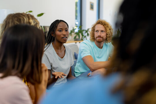 Group of diverse people sitting on sofa and talking in group therapy session