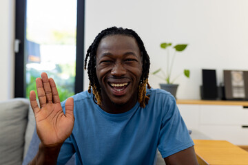 Happy african american man sitting on sofa and having video call