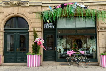 Fototapeta na wymiar Stylish bicycle with peonies flowers near shop entrance on city street
