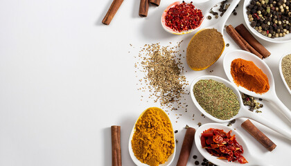 Spices in spoons and scattered on a white background with space for text