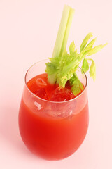 Glass of bloody mary with celery on pink background