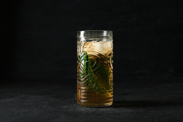 Glass of ice tea with mint on black background