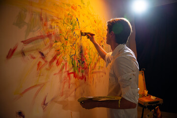 Closeup to the camera in the dark place artist man drawing new picture contemporary using the oil...
