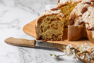 Delicious Italian Easter dove cake (traditional Colomba di Pasqua) and knife on white table, closeup