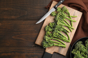 Fresh raw broccolini and knife on wooden table, flat lay with space for text. Healthy food
