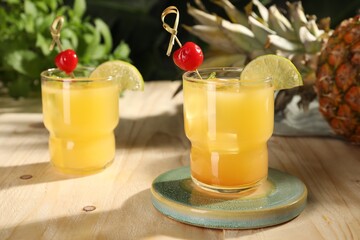 Tasty pineapple cocktails with cherry and lime on wooden table