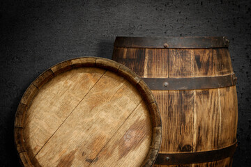 Two wooden barrels near dark textured wall
