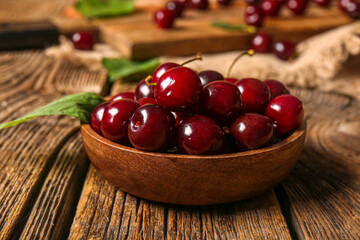 Bowl with sweet cherries on wooden table