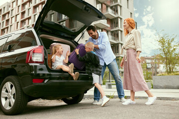 Young happy couple, family, man and woman gong on summer trip on car with the little children. Man...