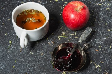 Still life - blueberry jam and herbal tea on the table. Sweet food on a dark background