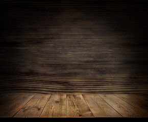  An empty wooden countertop against a black, dark concrete wall. Home interior. Evening, dim light. Space for text. Copy space
