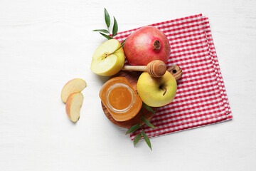 Board with jar of honey, pomegranate and apples for Rosh Hashanah celebration (Jewish New Year) on white wooden background