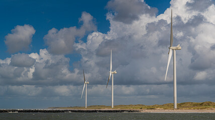 Windräder stehen an der Küste in den Dünen und erzeugen alternative Energie durch Wind