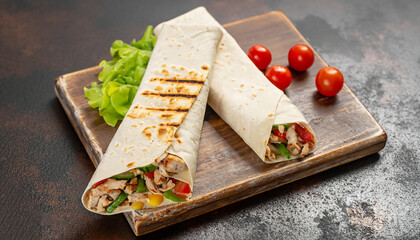 Burrito wraps with chicken and vegetables on a cutting board, against a background of concrete, Mexican shawarma