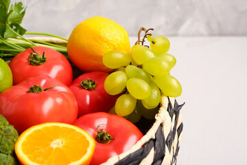 Wicker bowl with different fresh fruits and vegetables on white table, closeup