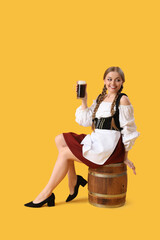 Beautiful Octoberfest waitress with beer sitting on yellow background