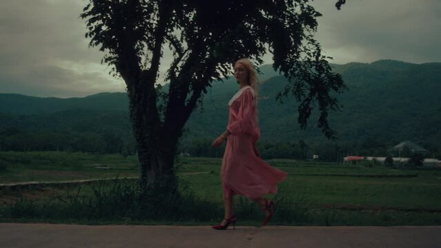 Woman in a vintage dress and red shoes walking down the road