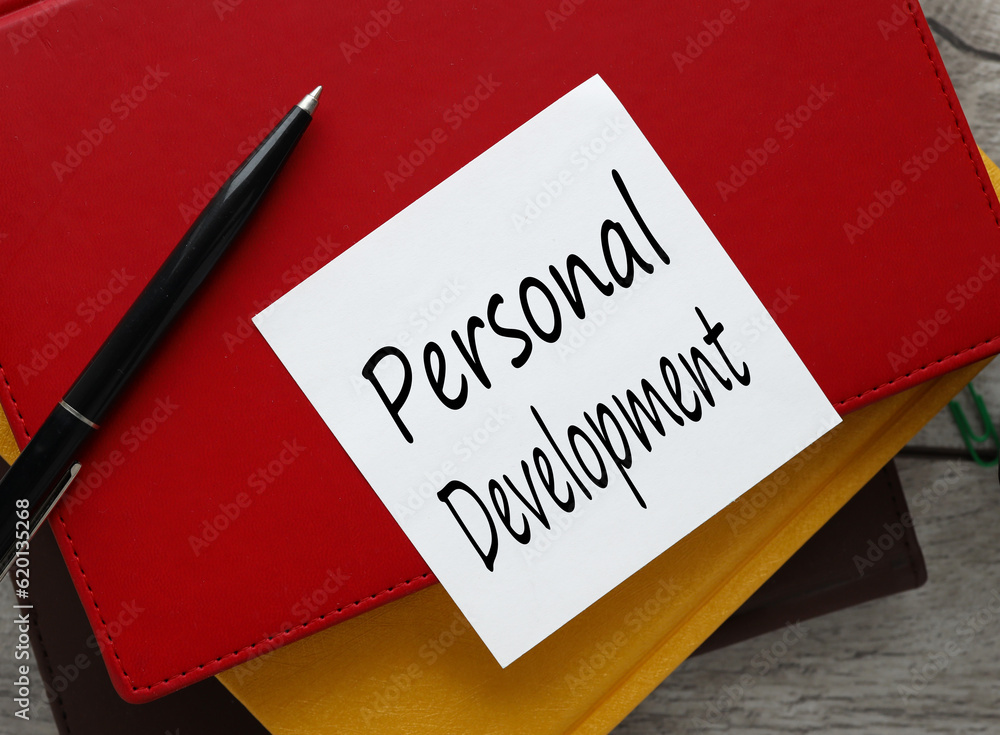 Aufkleber personal development view from above. workspace with text on a white sticker on a red notepad.