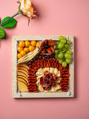 tabla de quesos en fondo rosado