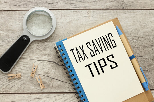 Tax Saving Tips text on a notepad page. near the magnifying glass on the working table