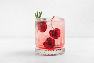Glass of tasty cherry lemonade with rosemary on white background