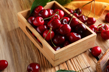 Box with sweet cherries on wooden background