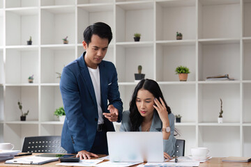 Two business people being stressed while working on a laptop in an office, Business partners working together, Collaborating teamwork analyzing paperwork data, business reports