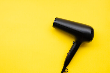 Black hair dryer on blue and yellow paper background