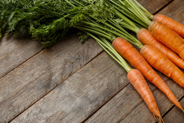 Fresh carrots with leaves on wooden background