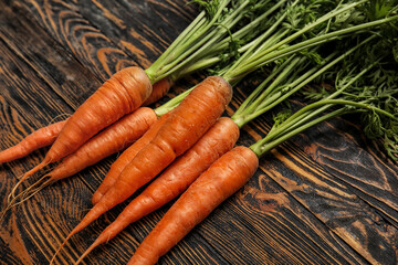 Fresh carrots with leaves on wooden background