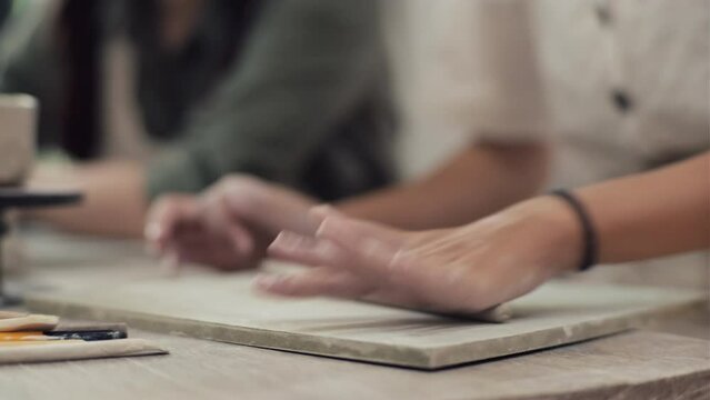 Female hands showing another person how to sculpt figure out of clay at masterclass in workshop